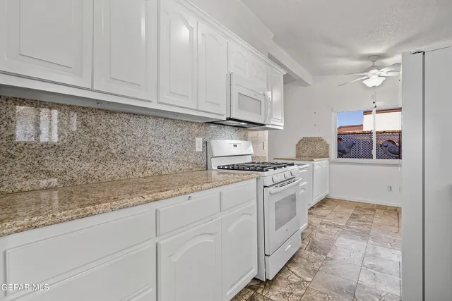 a kitchen with granite countertop white cabinets and white appliances
