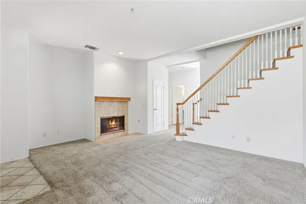 a view of an empty room with wooden floor fireplace and a window