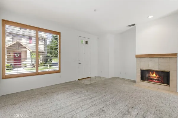 a view of an empty room with a window and fireplace