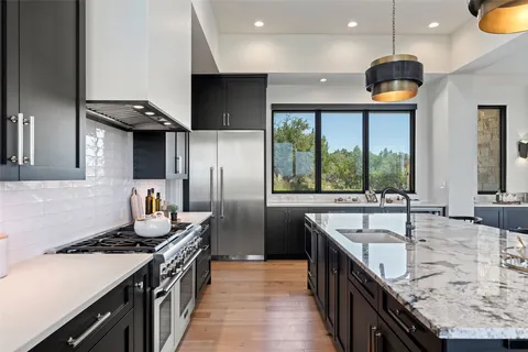 a kitchen with granite countertop a sink a counter space appliances and cabinets