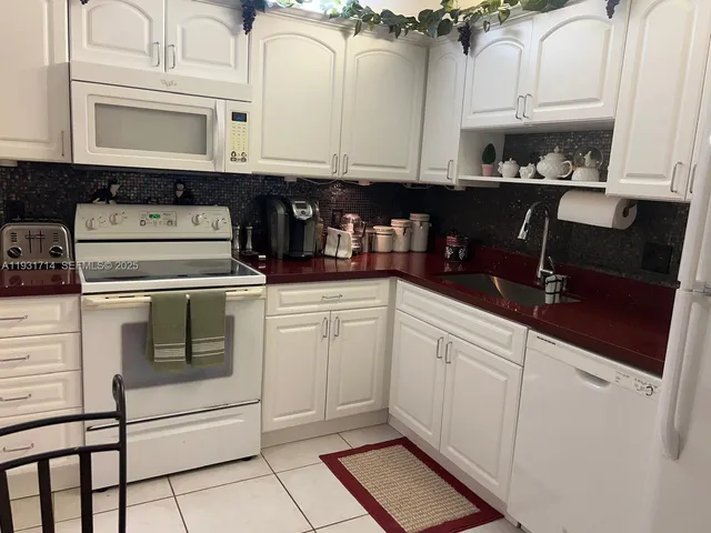 a kitchen with white cabinets and white appliances