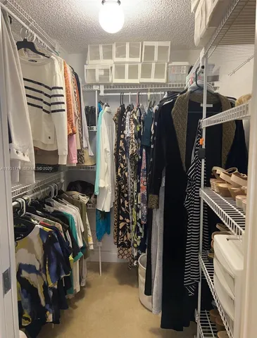 a view of walk in closet with clothes and shoes