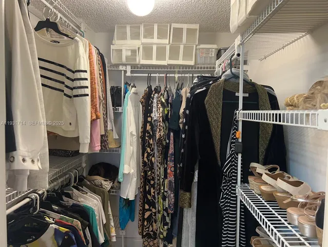 a view of walk in closet with clothes and shoes