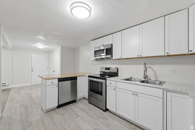 831 Lennox Street, Unit 5 Midvale, UT 84047 - Photo 10 of 19 Kitchen featuring stainless steel appliances, white cabinets, a peninsula, light wood-style flooring, and a textured ceiling