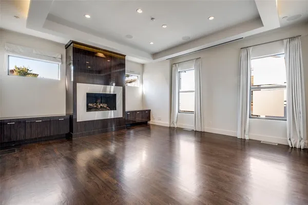 an empty room with wooden floor fireplace and windows