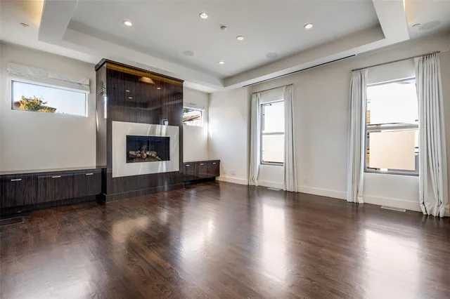 an empty room with wooden floor fireplace and windows