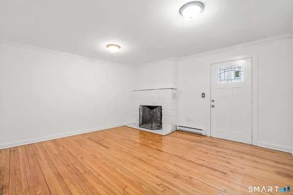 a view of empty room with wooden floor and fireplace