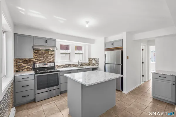 a kitchen with granite countertop a sink stove and refrigerator