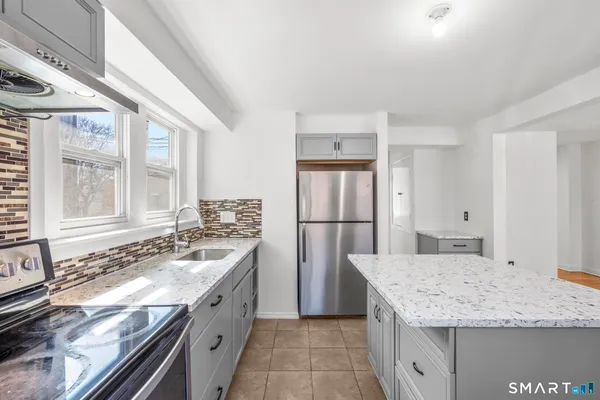 a kitchen with granite countertop a sink stove and refrigerator