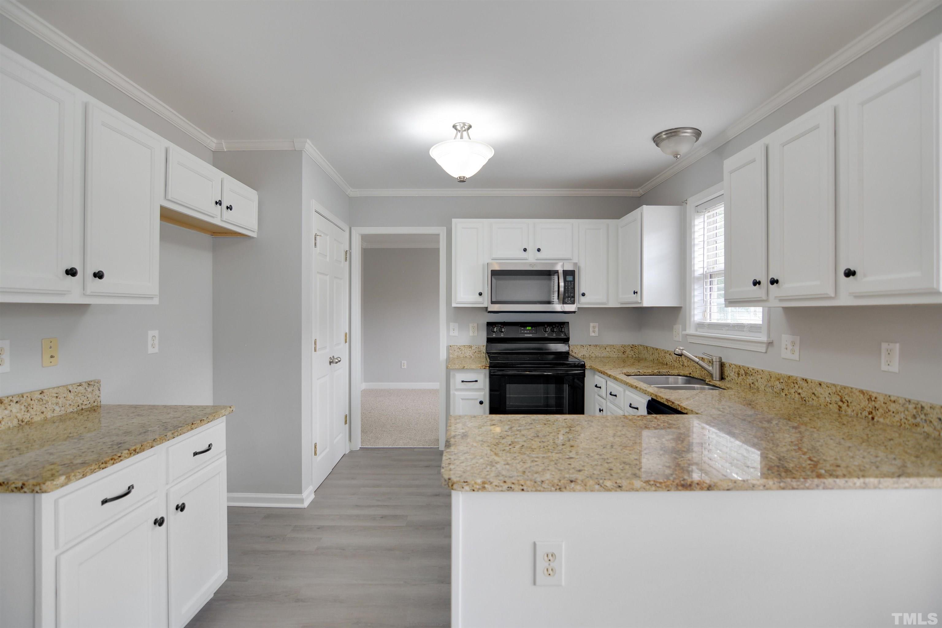 9221 Pennythorne Court Raleigh, NC 27615 - Photo 5 of 23 a kitchen with stainless steel appliances granite countertop a sink a stove and a refrigerator