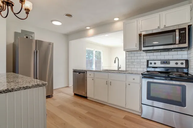 a kitchen with granite countertop stainless steel appliances a sink stove and microwave