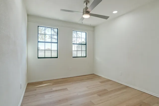 an empty room with a ceiling fan and wooden floor