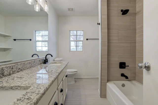 a bathroom with a granite countertop sink a toilet and a mirror