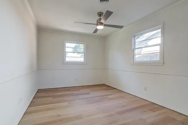 an empty room with wooden floor closet and windows