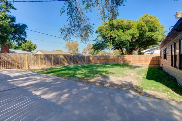 a view of a yard in front of a house with large tree