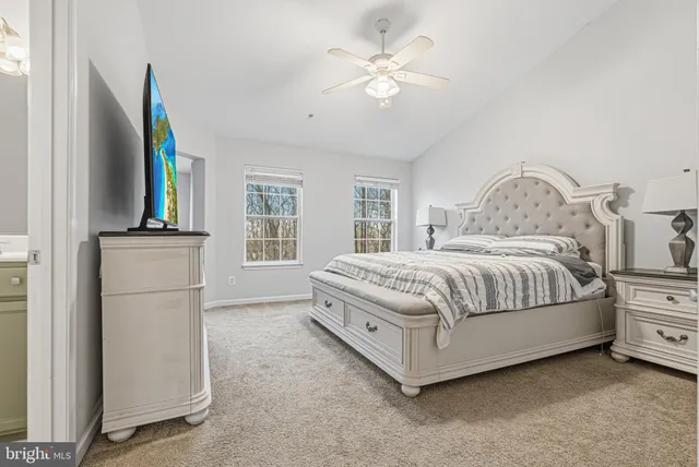 a bedroom with a large bed a chandelier and a flat tv screen on dresser