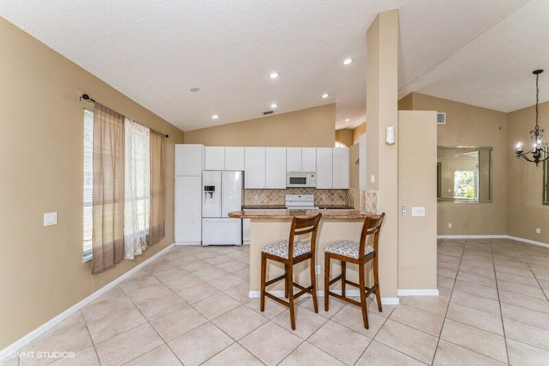 6427 Wild Olive Lane Stuart, FL 34997 - Photo 3 of 11 a kitchen with stainless steel appliances kitchen island granite countertop a refrigerator and cabinets