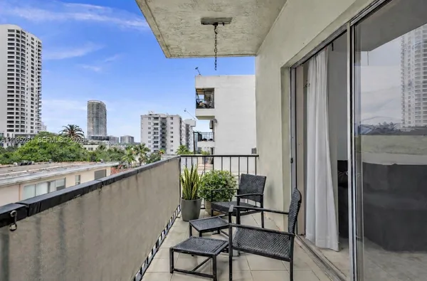 a balcony with table and chairs and potted plants with wooden floor