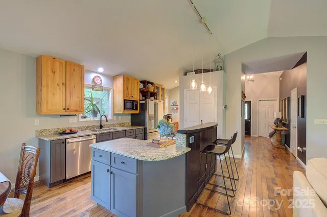 a kitchen with stainless steel appliances granite countertop a sink a stove and wooden cabinets