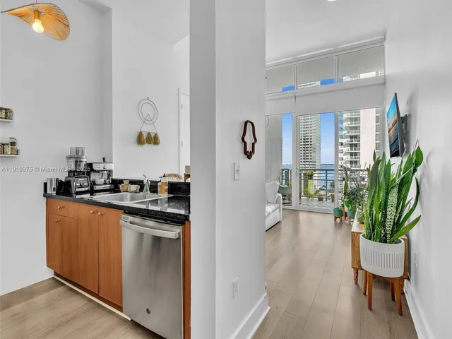 a living room with stainless steel appliances furniture a potted plant and a wooden floor