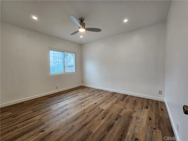 an empty room with wooden floor chandelier fan and windows