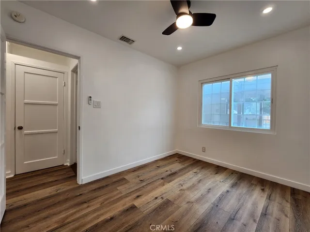 an empty room with wooden floor chandelier fan and windows