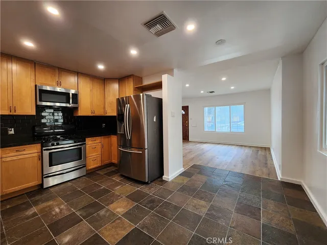 a kitchen with stainless steel appliances granite countertop a refrigerator a stove a sink and a microwave