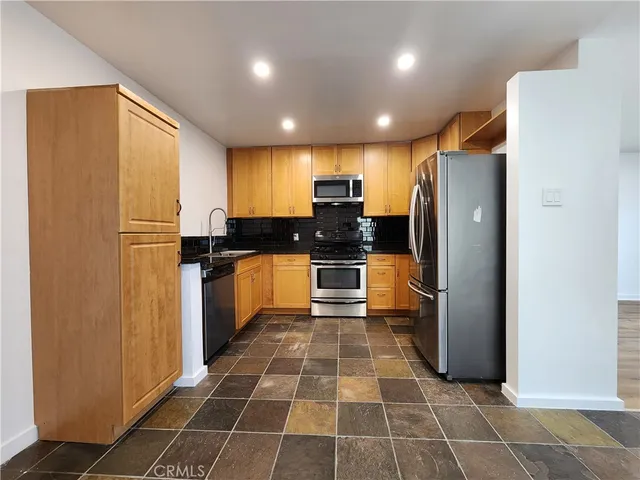 a kitchen with stainless steel appliances granite countertop a refrigerator a stove a sink and a microwave