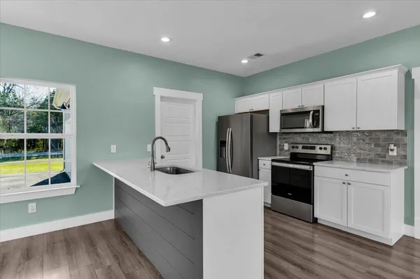 a kitchen with white cabinets stainless steel appliances and a counter space