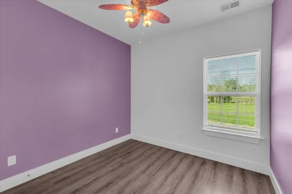 a view of an empty room with window and wooden floor