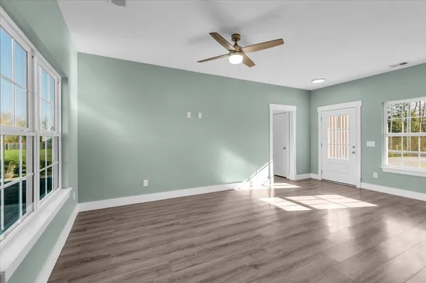 a view of an empty room with a window and wooden floor