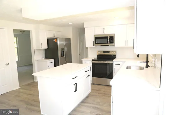 a kitchen with white cabinets and sink