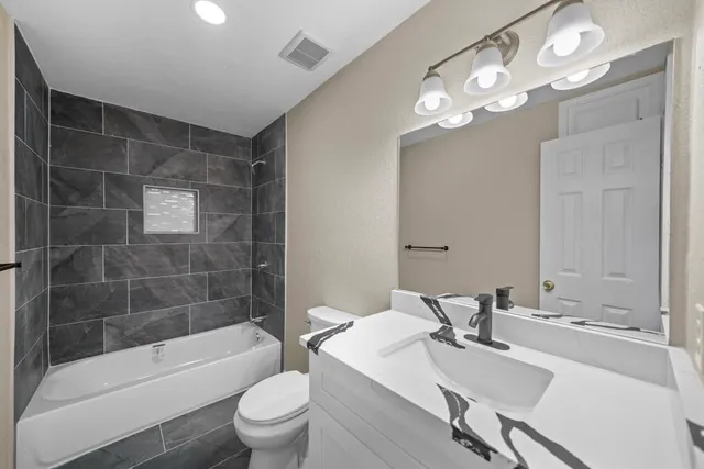 a bathroom with a sink a toilet a mirror and shower