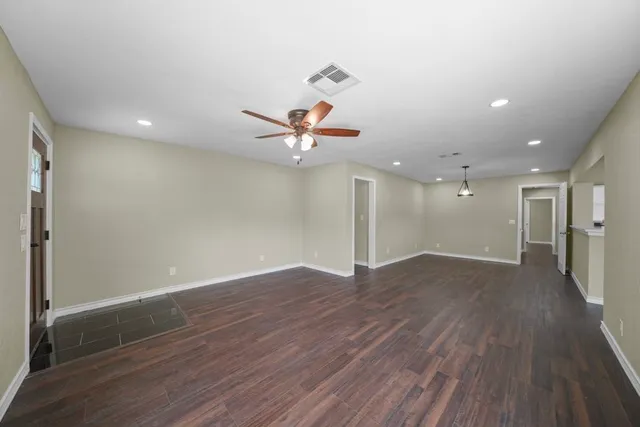 an empty room with wooden floor ceiling fan and window