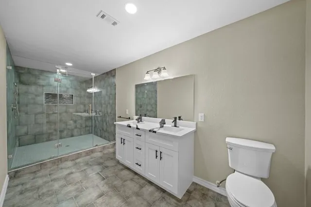 a bathroom with a double vanity sink toilet and shower