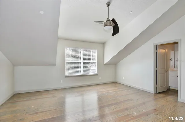a view of an empty room with wooden floor and windows