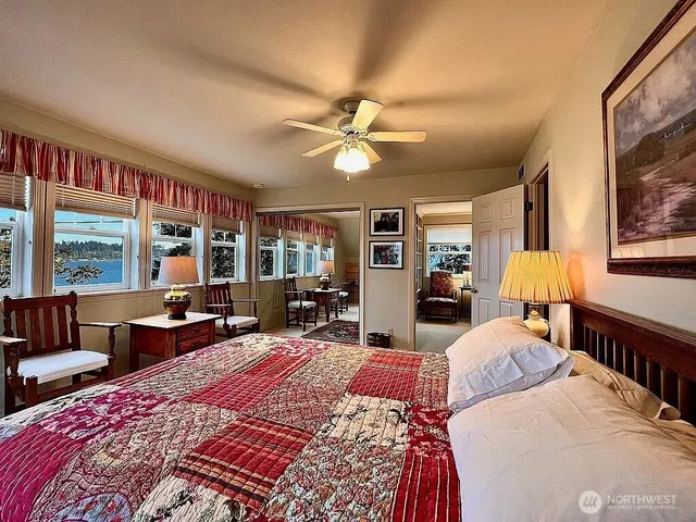 a bedroom with a bed a large window and book shelf