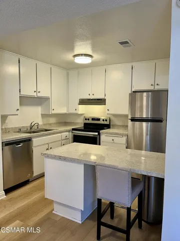 a kitchen with a dining table chairs refrigerator and cabinets