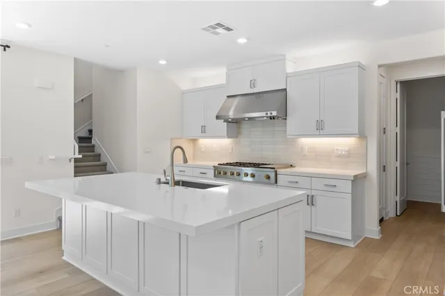 a kitchen that has a sink a stove and wooden floor