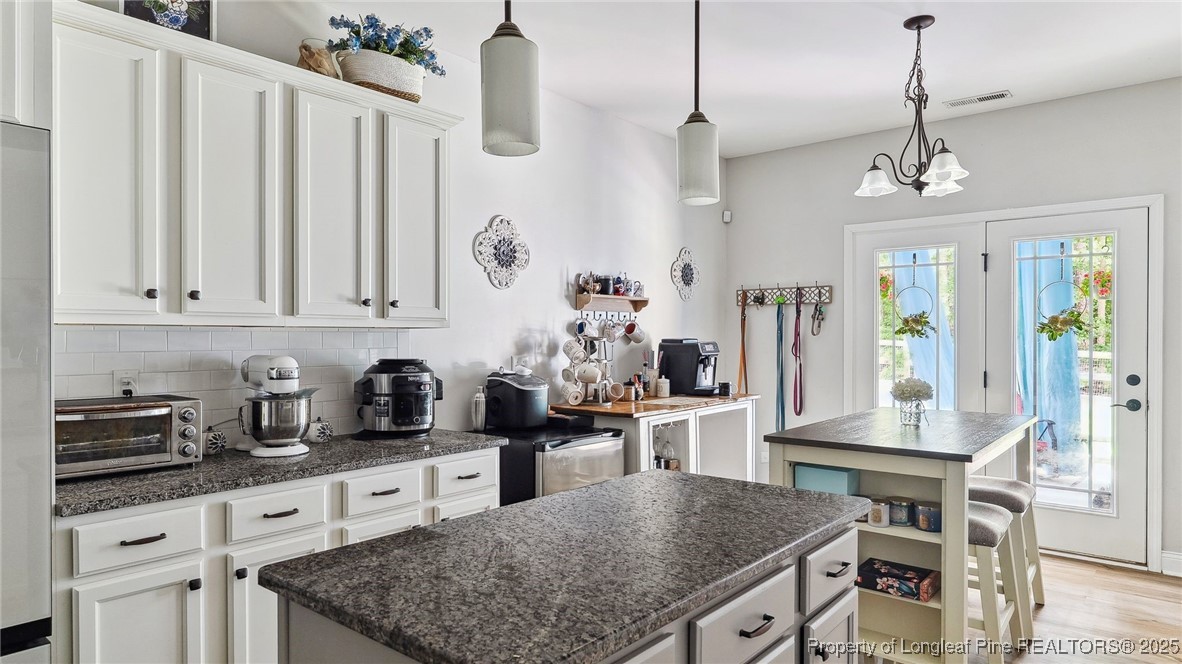 75 Bynum Court Carthage, NC 28327 - Photo 16 of 49 a kitchen with stainless steel appliances granite countertop a stove a sink dishwasher and white cabinets with wooden floor