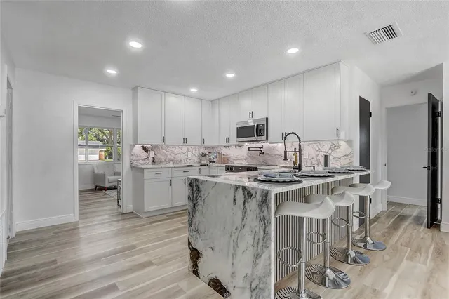 a view of an empty room with wooden floor and a ceiling fan