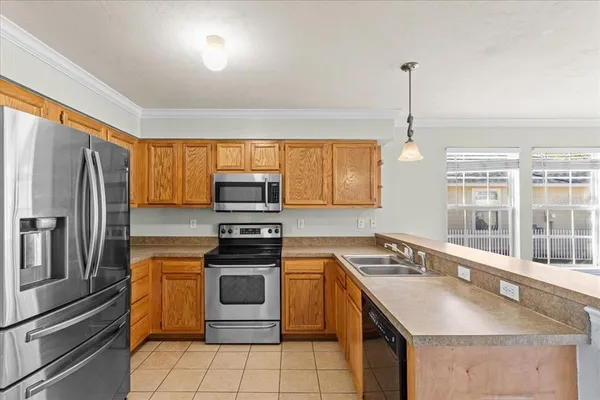 a kitchen that has a sink stainless steel appliances a window and a counter top space