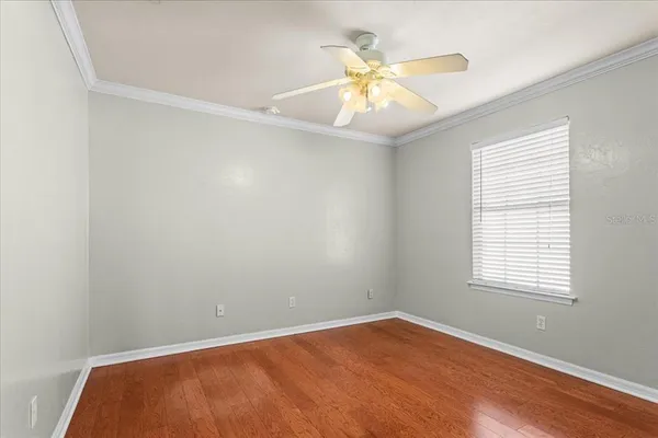 an empty room with a chandelier fan and windows