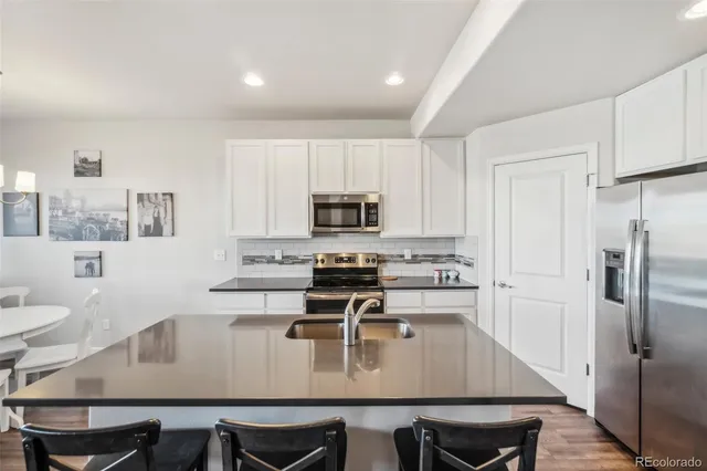 a kitchen with a dining table chairs and refrigerator