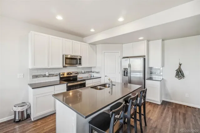 a kitchen with stainless steel appliances granite countertop a stove a refrigerator a sink a stove and island with wooden floor