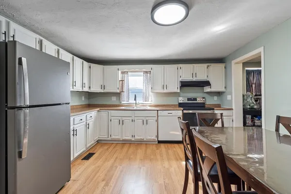 a kitchen with stainless steel appliances granite countertop a dining table chairs refrigerator and sink