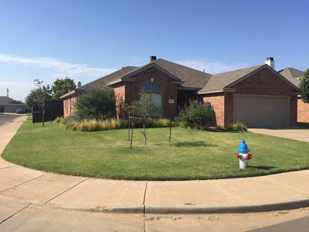 a front view of a house with a yard and potted plants