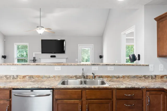 a kitchen with granite countertop a sink and a flat screen tv
