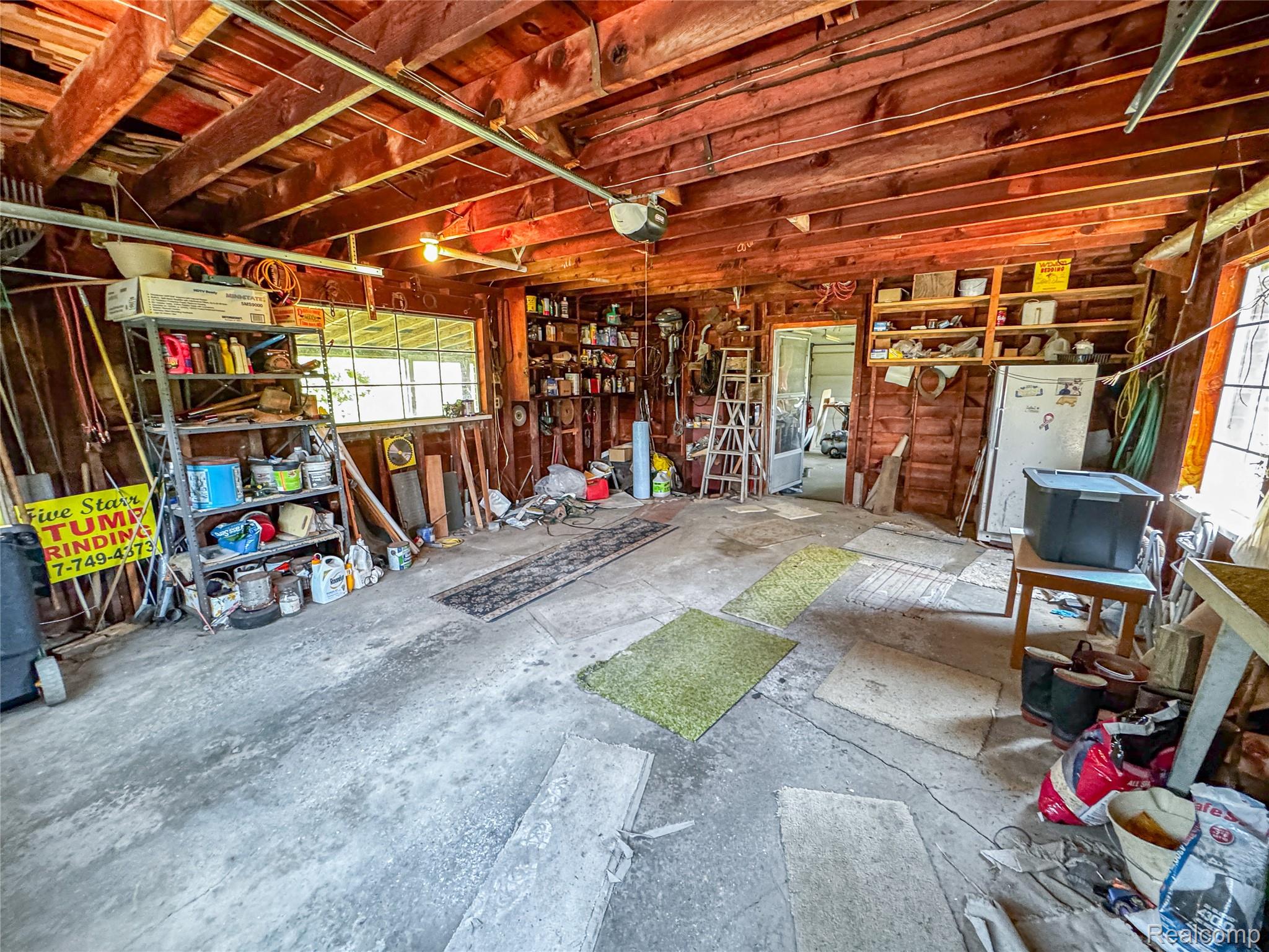 11651 South New Lothrop Road Byron, MI 48418 - Photo 10 of 19 Spacious garage with exposed wood beam ceiling, concrete flooring, and multiple windows providing natural light