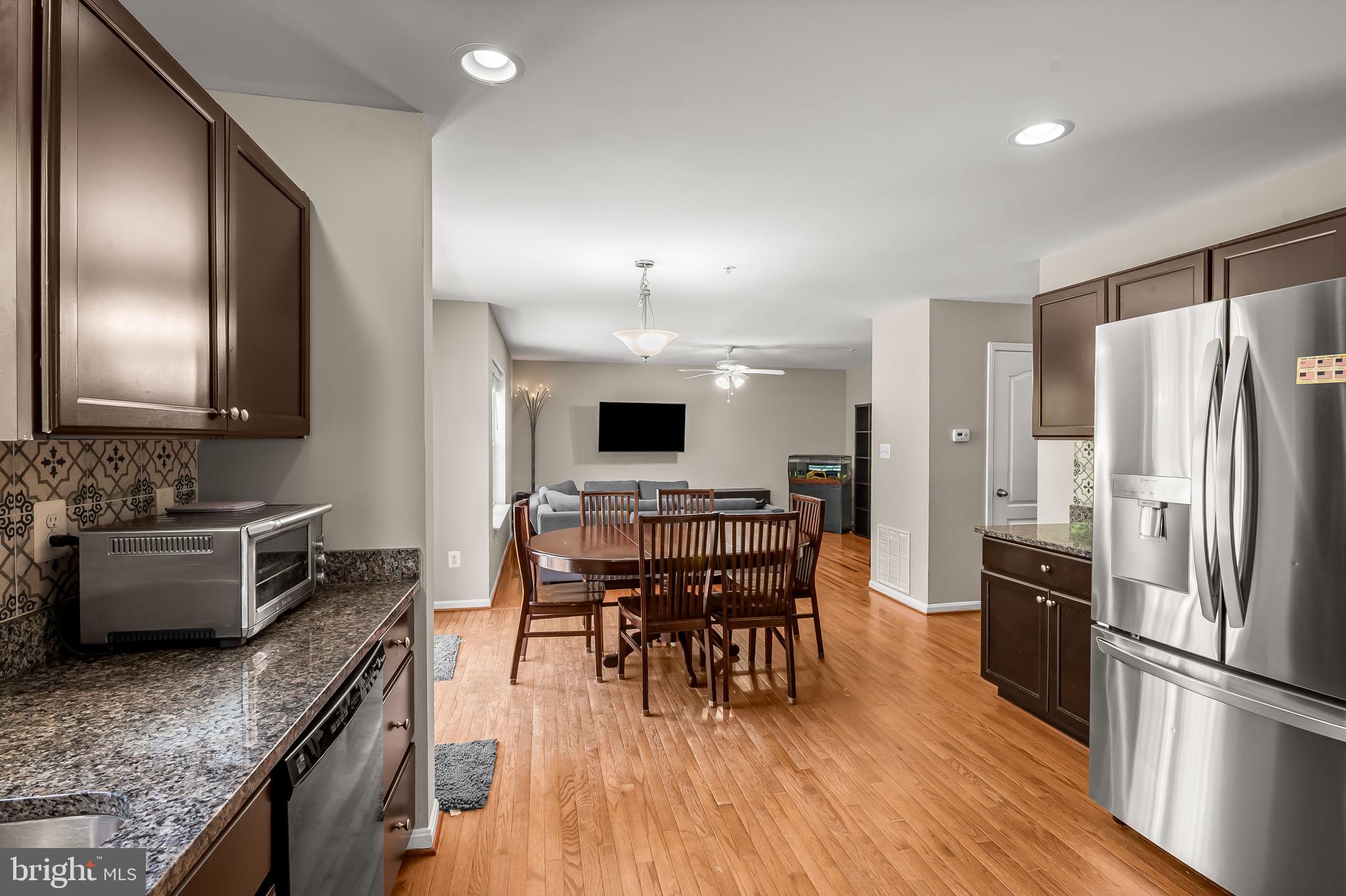 6008 Hanover Road Elkridge, MD 21075 - Photo 14 of 36 a kitchen with stainless steel appliances granite countertop a stove a refrigerator a sink a dining table and chairs with wooden floor
